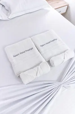 two white towels sitting on a white bed at Apart-Hotel Prestige in Ulcinj