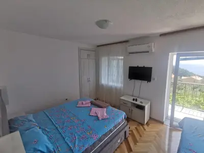 a bedroom with a blue bed and a television at Apartments Djedovic 2 in Petrovac na Moru
