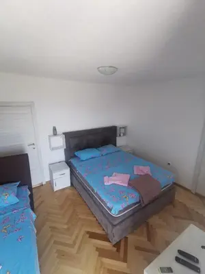a bedroom with two beds and a wooden floor at Apartments Djedovic 2 in Petrovac na Moru