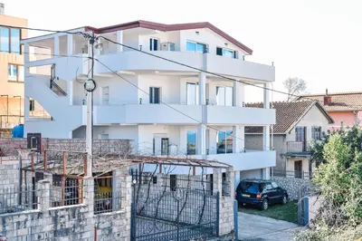 a white building with a car parked in front of it at Seaview Apartments Bonaca in Bar