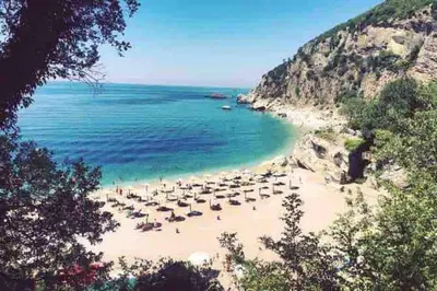 a beach with chairs and umbrellas and the ocean at Horizon Two bedroom Penthouse with Hot tub in Becici