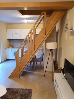 a wooden staircase in a living room with a table at Village house DUNJA in Virpazar