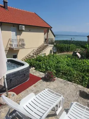 a patio with two white chairs and a hot tub at Village house DUNJA in Virpazar