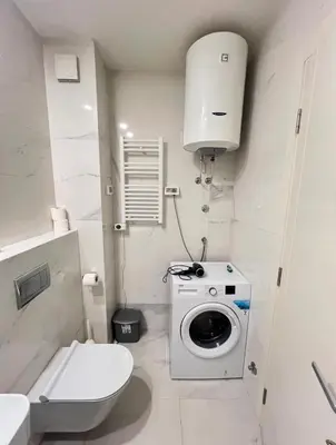 a bathroom with a washing machine and a toilet at White Homes 1BR - Central Point in Podgorica