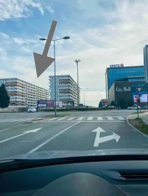 a street sign with an arrow on a city street at White Homes 1BR - Central Point in Podgorica