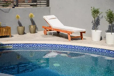 a white chair sitting next to a swimming pool at Luxury Scandinavian - Villa Montenegro in Ulcinj