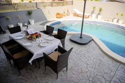 a dining table and chairs next to a swimming pool at Luxury Scandinavian - Villa Montenegro in Ulcinj
