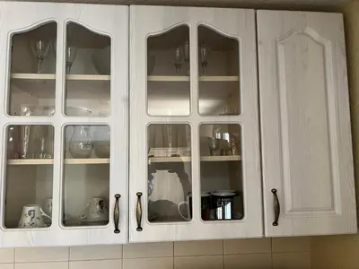 a white cabinet with glass doors in a kitchen at Green Hills II by Rent a car MI in Podgorica