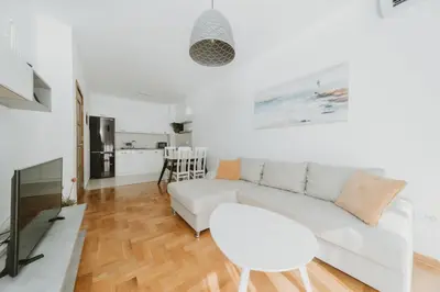 a white living room with a white couch and a table at Modern Spacious Fully Equipped One Bedroom Apartment in Budva, Free Parking, Ideal for Long Stays in Budva