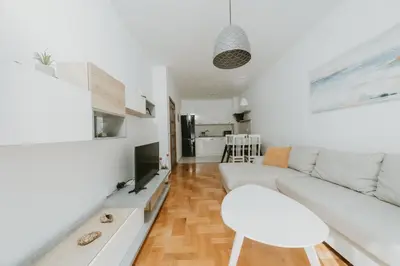 a white living room with a white couch and a chair at Modern Spacious Fully Equipped One Bedroom Apartment in Budva, Free Parking, Ideal for Long Stays in Budva