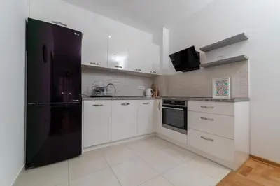 a kitchen with white cabinets and a black refrigerator at Modern Spacious Fully Equipped One Bedroom Apartment in Budva, Free Parking, Ideal for Long Stays in Budva