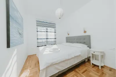 a white bedroom with a bed and a window at Modern Spacious Fully Equipped One Bedroom Apartment in Budva, Free Parking, Ideal for Long Stays in Budva
