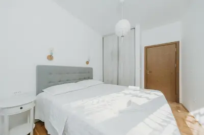 a white bedroom with a white bed and a wooden floor at Modern Spacious Fully Equipped One Bedroom Apartment in Budva, Free Parking, Ideal for Long Stays in Budva