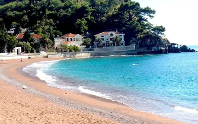 a sandy beach with houses and the ocean at Petrovac Holiday apartments 1 in Petrovac na Moru