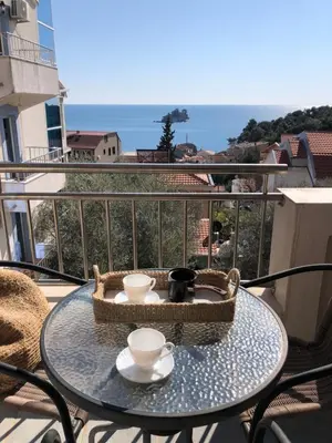 a table with two cups and a basket on a balcony at Petrovac Holiday apartments 1 in Petrovac na Moru