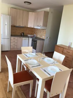 a kitchen with a table and chairs and a kitchen with a white refrigerator at Petrovac Holiday apartments 1 in Petrovac na Moru