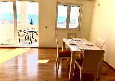 a dining room with a table and chairs and a balcony at Petrovac Holiday Apartments 2 in Petrovac na Moru