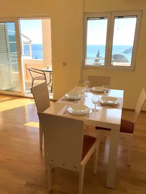 a dining room with a table and chairs and the ocean at Petrovac Holiday Apartments 2 in Petrovac na Moru