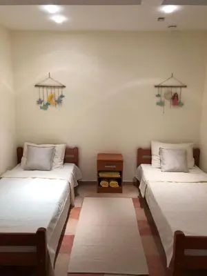 a room with two beds and a table between them at Petrovac Holiday Apartments 2 in Petrovac na Moru