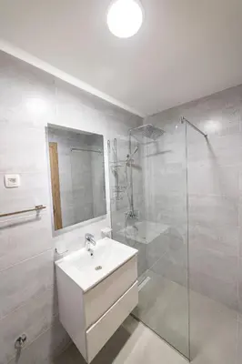 a white bathroom with a sink and a shower at Apartments 28 Master Quart in Podgorica