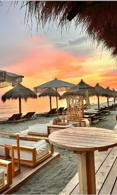 a beach with tables and chairs and umbrellas at Apartments Plaza in Ulcinj