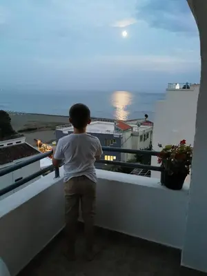 a young boy standing on a balcony looking at the ocean at Apartments Plaza in Ulcinj