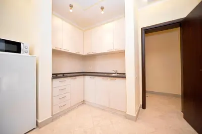 an empty kitchen with white cabinets and a refrigerator at Rafailovici Holiday Apartments in Rafailovici