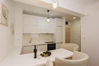 a white kitchen with a plate of food on a table at Status-M Apartments 135 in Becici