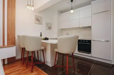 a kitchen with white cabinets and white stools at Status-M Apartments 135 in Becici