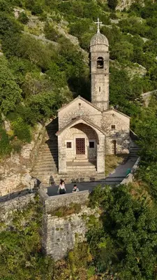 two people sitting in front of a church with a tower at Little Bay Apartments in Kotor
