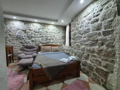 a bedroom with a bed and a stone wall at Little Bay Apartments in Kotor