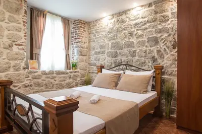 a bedroom with a bed with a stone wall at Little Bay Apartments in Kotor