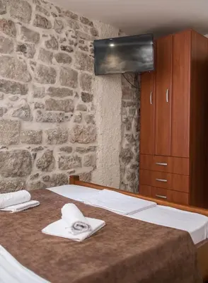 a bedroom with a bed and a stone wall at Little Bay Apartments in Kotor