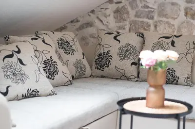 a couch with pillows and a vase of flowers on a table at Little Bay Apartments in Kotor