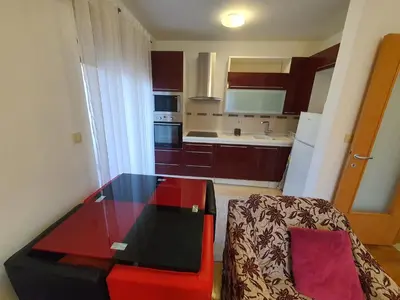 a small kitchen with a table and a red chair at Comfort one bedroom apartment in Podgorica
