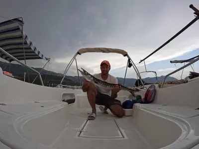 a man sitting on a boat holding a fish at Davidoff Branko Kalezic in Budva