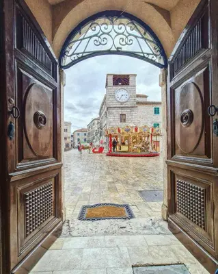 an open door to a building with a clock tower at Apartman J&I in Kotor