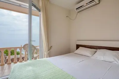 a bedroom with a bed and a large window at Apartman -PANORAMA LUX in Sutomore