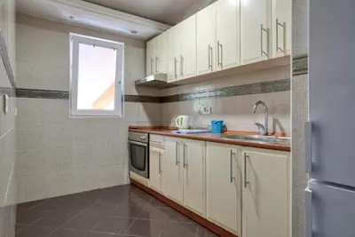 a kitchen with white cabinets and a window at Apartman -PANORAMA LUX in Sutomore