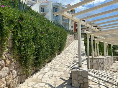 a stone walkway next to a building with a wooden structure at Modern apartment with sea view in Dobra Voda, 95 m², Pool in Dobra Voda
