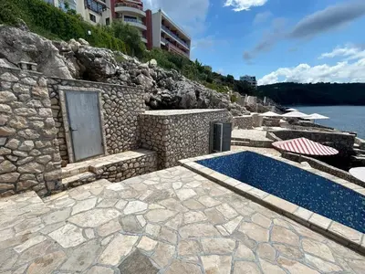 a swimming pool next to a building and the water at Modern apartment with sea view in Dobra Voda, 95 m², Pool in Dobra Voda