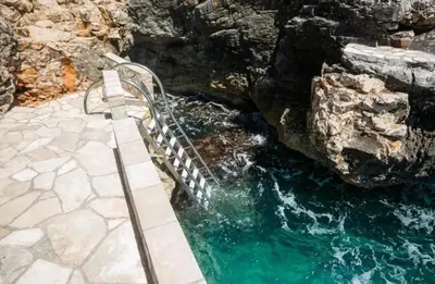 a bench next to a pool of water at Modern apartment with sea view in Dobra Voda, 95 m², Pool in Dobra Voda