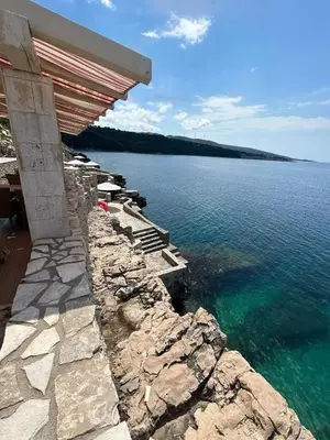 a building on the shore of a body of water at Modern apartment with sea view in Dobra Voda, 95 m², Pool in Dobra Voda