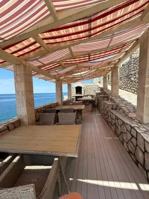 a patio with tables and chairs and the ocean at Modern apartment with sea view in Dobra Voda, 95 m², Pool in Dobra Voda