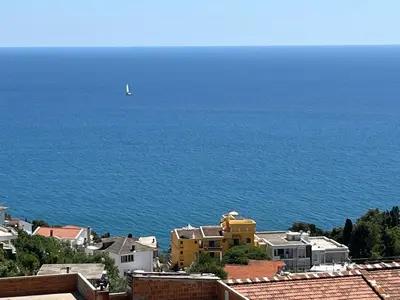 a sailboat in the ocean with houses and a city at Art's Apartment mit Pool Ulcinj Pinjes in Ulcinj