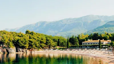 a body of water with chairs and mountains in the background at Varja 3 Apartment in Pržno
