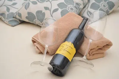 a bottle of wine on a towel with two wine glasses at Apartman Bojanic in Podgorica