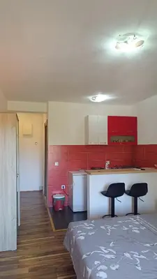 a kitchen with red cabinets and two black chairs in a room at Apartmani Maša in Budva