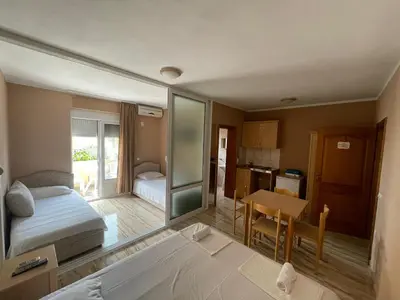 a bedroom with a bed and a table and a kitchen at Mali Medved Ulcinj in Ulcinj