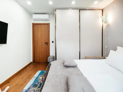 a bedroom with a large white bed and a wooden door at The Luxury Maison W Nest - 2 bedroom apartment in Kotor